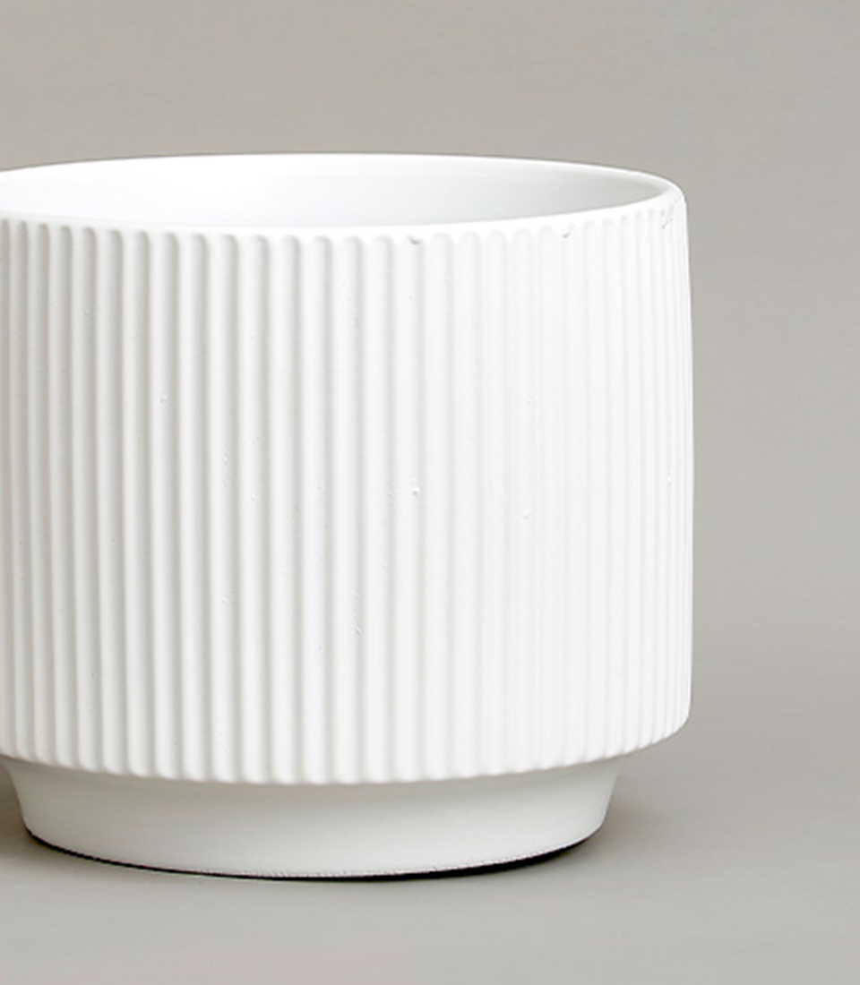 Close-up of a White ribbed ceramic vase with a modern design.