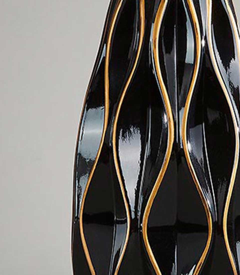 Close-up of black ceramic vase with gold wavy lines