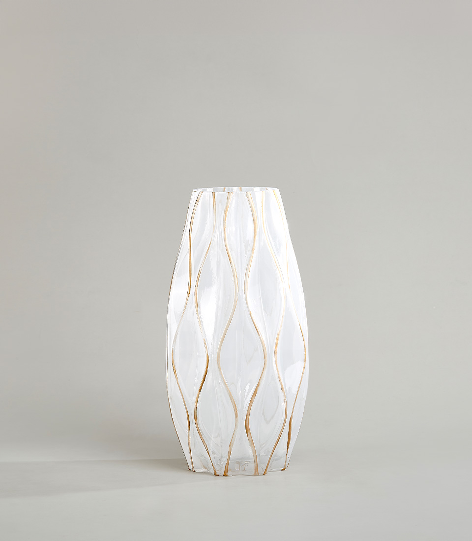 White ceramic vase with gold accents and wavy design against a neutral background.