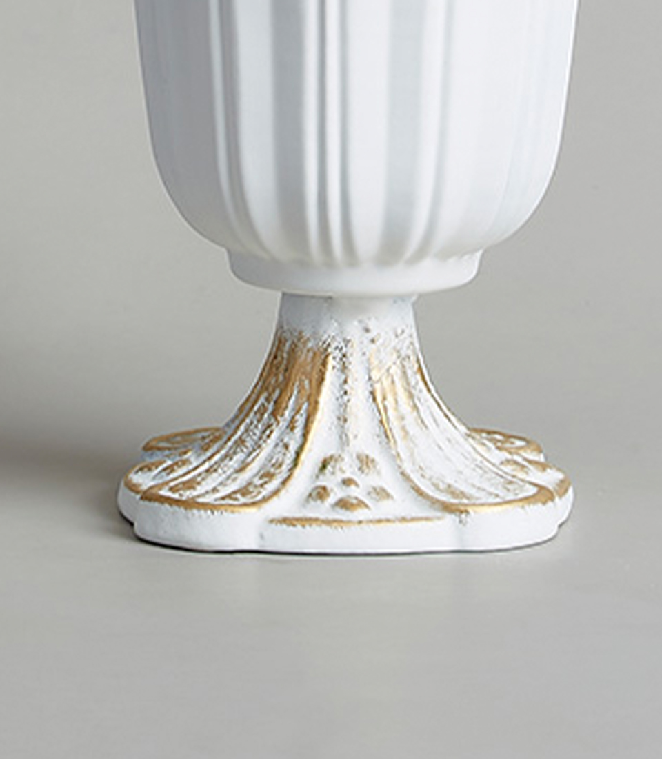 Close-up of an Base of an elegant stainless steel vase with gold detailing and a fluted design.