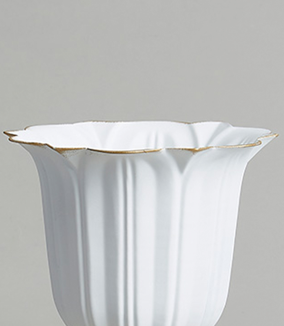 Close-up of an elegant stainless steel vase with gold detailing on the rim and a classic fluted design.