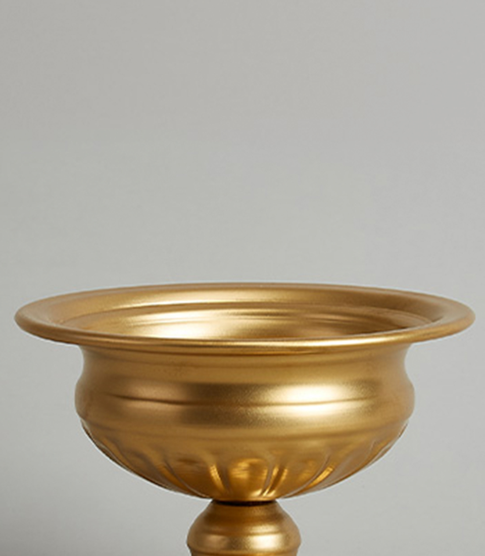 Close-up of elegant gold steel pedestal vase with a wide bowl and fluted base design.