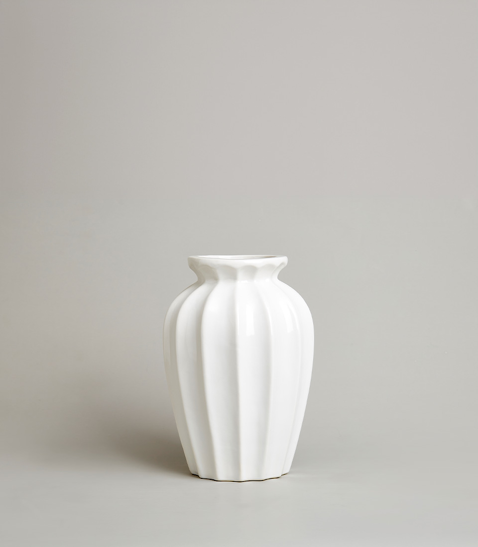 Elegant white ceramic vase with a fluted design, on a light grey background.