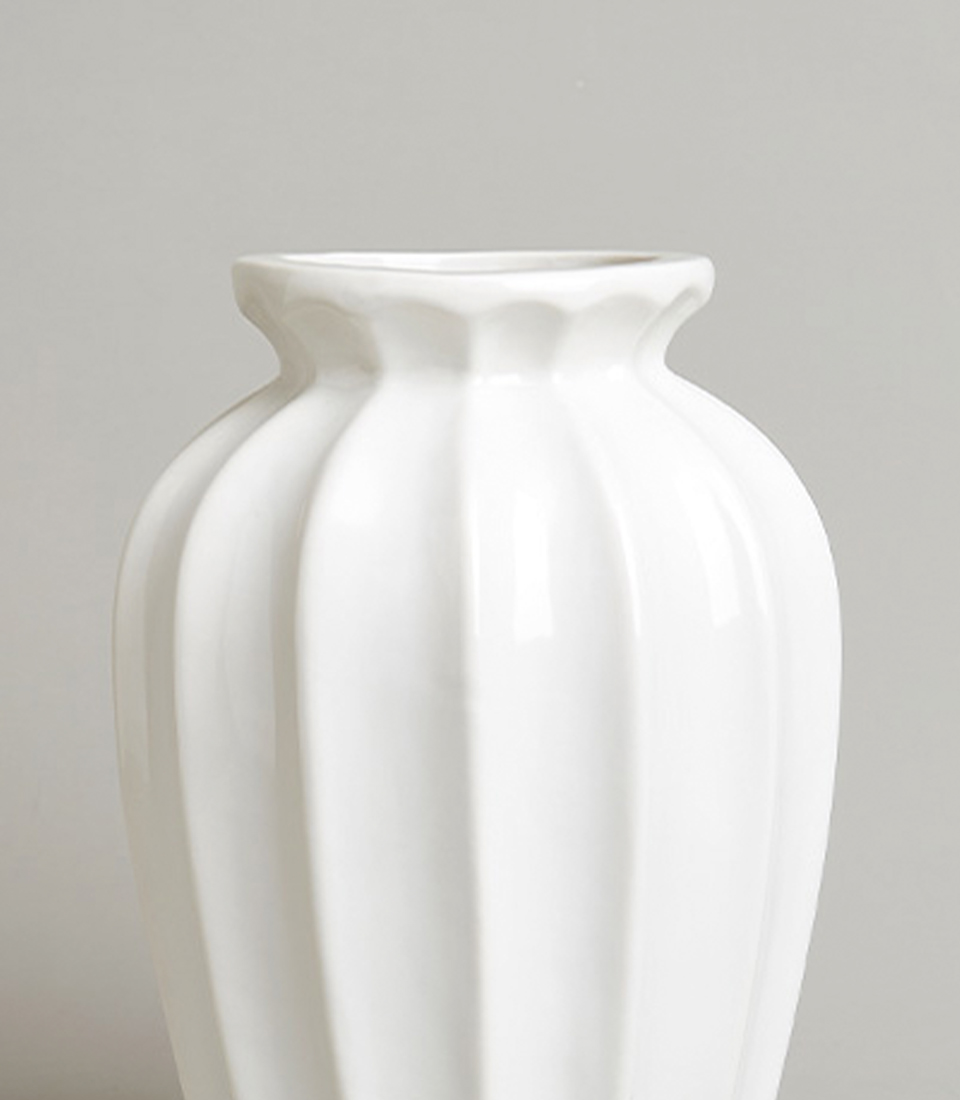 Close-up of elegant white ceramic vase with a fluted design.