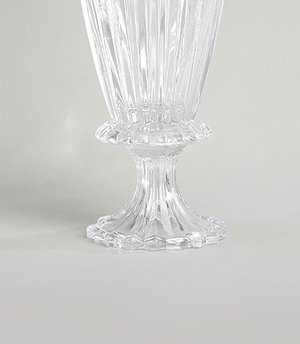Close-up view of the base of a tall crystal glass mirror vase with intricate faceted design on a white background