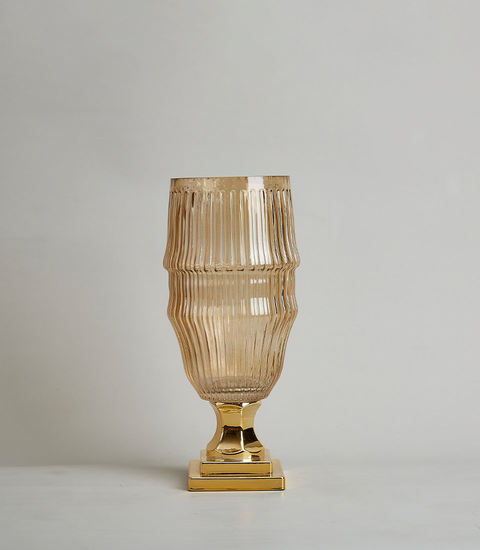 Elegant amber glass vase with a ribbed texture and gold base on a white background.