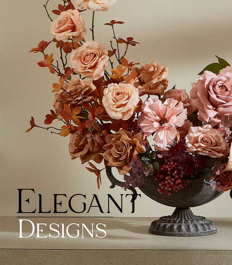 Artificial flower arrangement in decorative vase with pink, brown and peach flowers on a beige table and against a beige background with the 