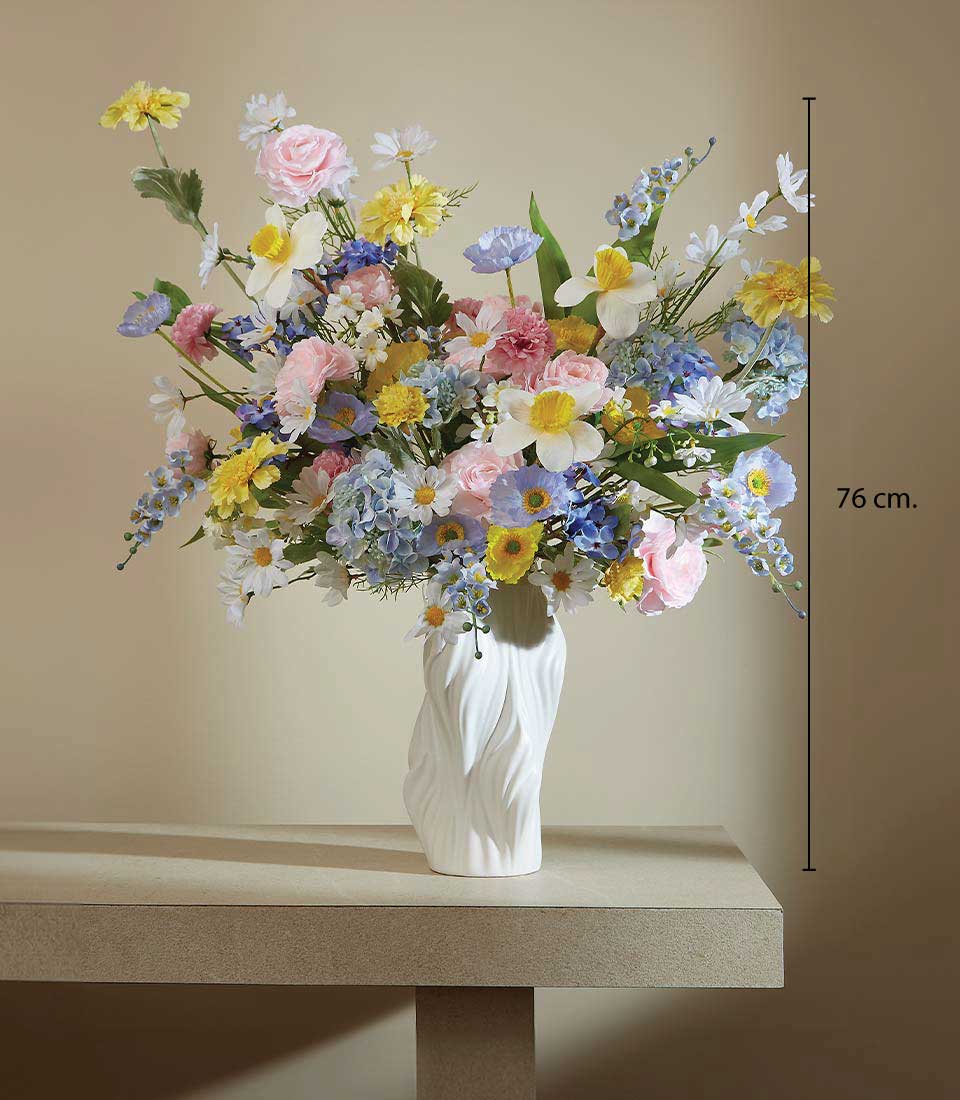 Artificial flower arrangement with pastel-colored daisies, roses, and hydrangeas in a sleek white vase on a table, displayed on a beige background, featuring a height measurement of 76 cm.