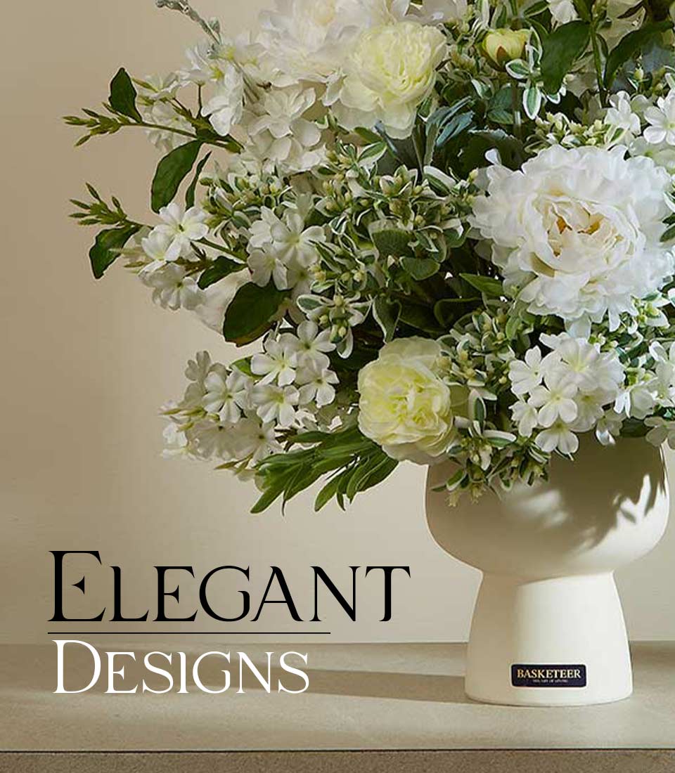 Artificial white flower arrangement with green foliage in a modern white ceramic vase on a table with text 