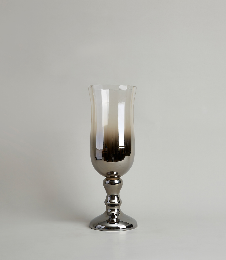Elegant tall glass vase with a metallic gradient finish and a sturdy pedestal base, on a light gray background.