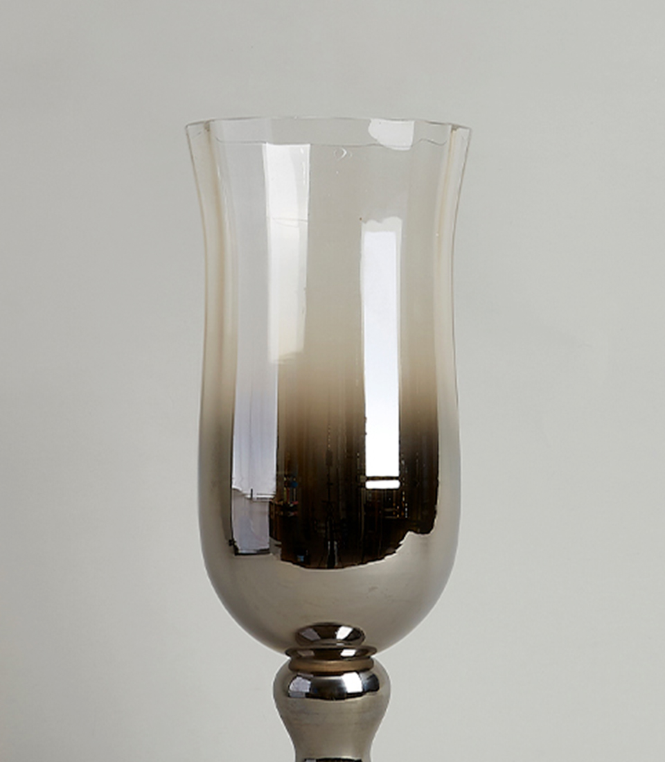 Close-up of a tall glass vase with a metallic gradient finish, showcasing its elegant and reflective surface.