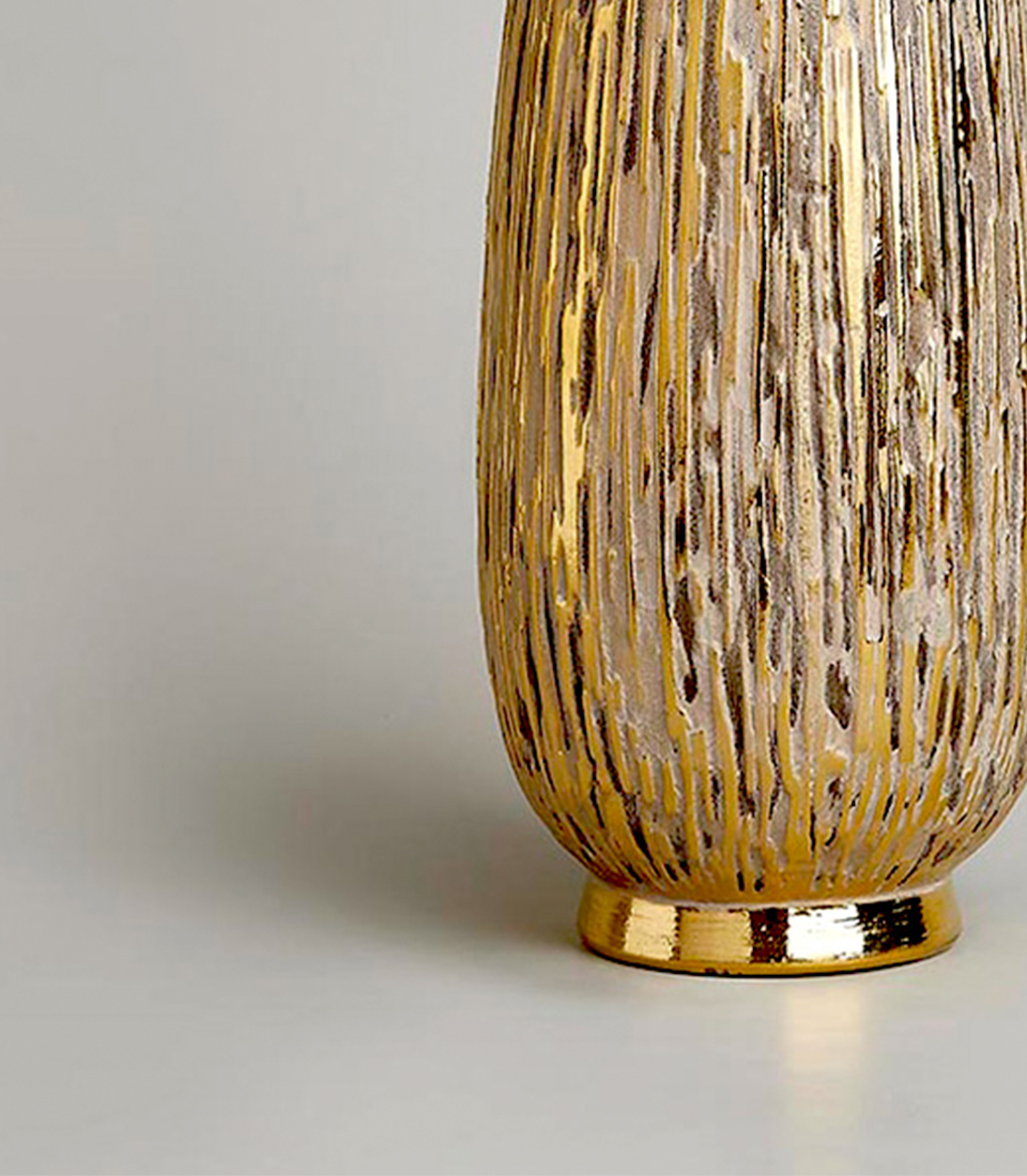 Elegant gold textured vase with detailed patterns, standing on a light background.