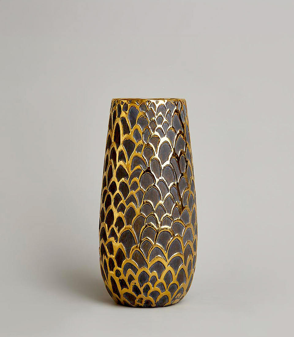 Gold and black textured vase with unique fish scale pattern on a light gray background.