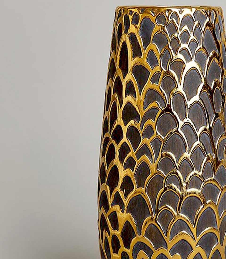 Close-up of a gold and black vase with a detailed fish scale pattern