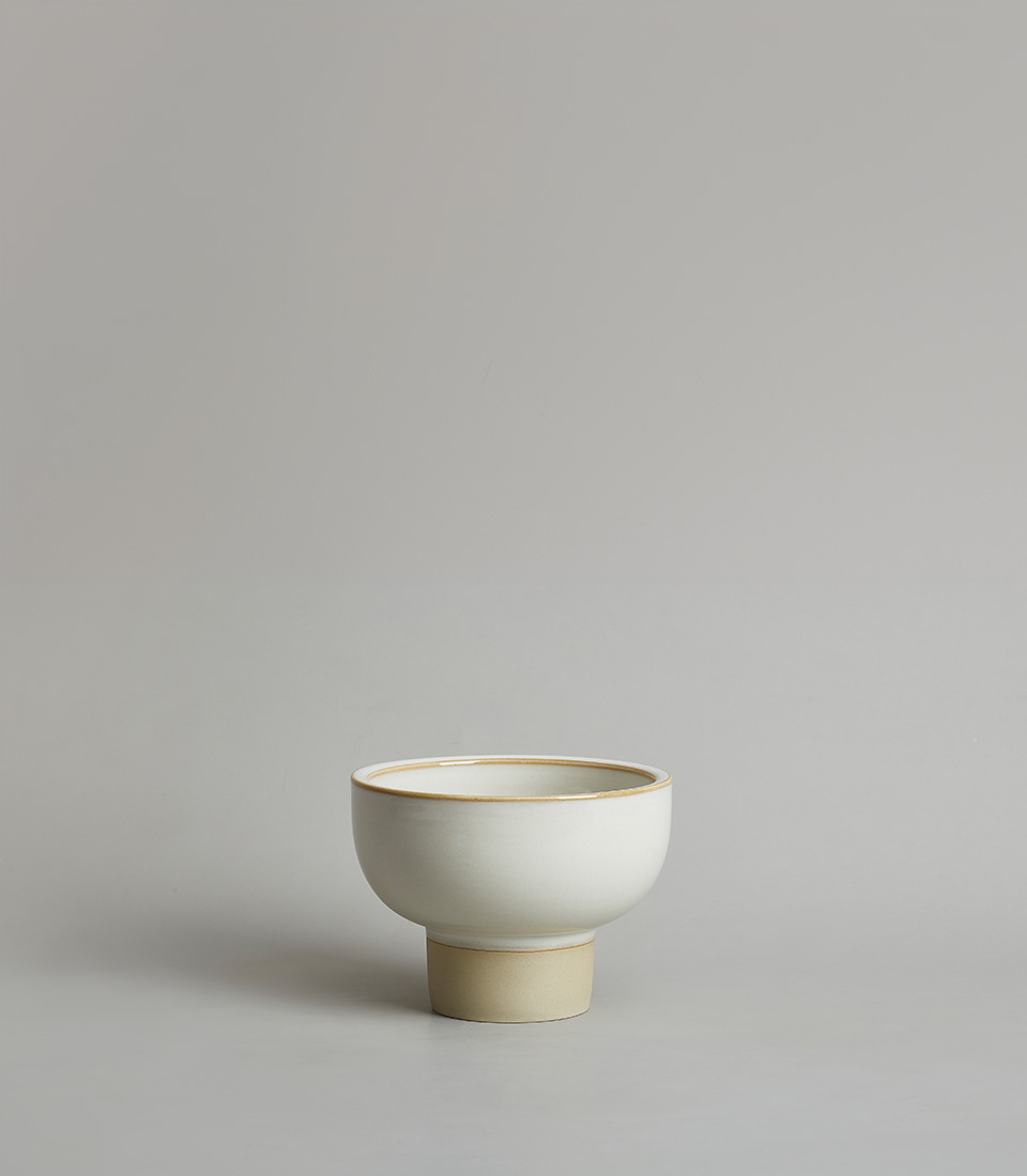 Minimalist white ceramic pedestal bowl vase on a light gray background.