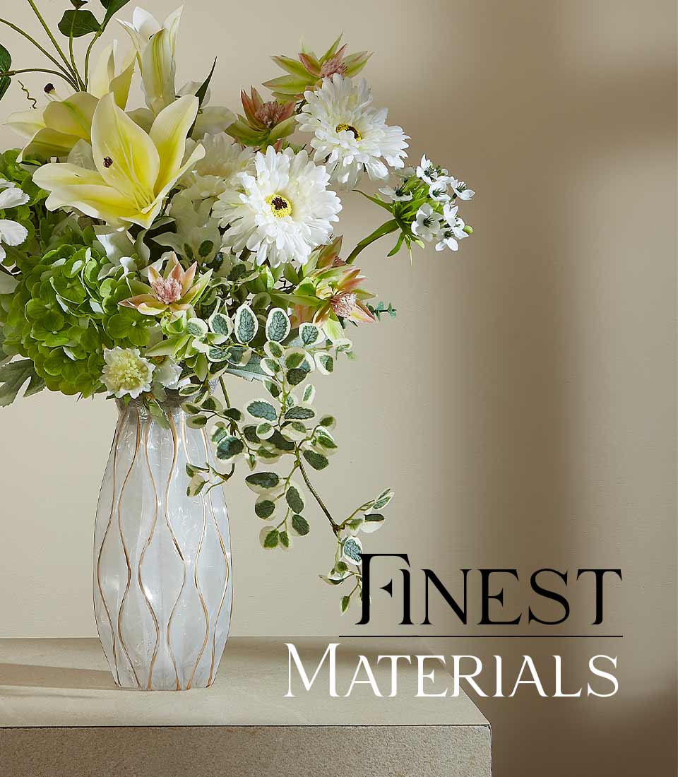 Close-up of an Artificial flower arrangement featuring white lilies, daisies, green hydrangeas, and foliage in a modern textured vase, with a 