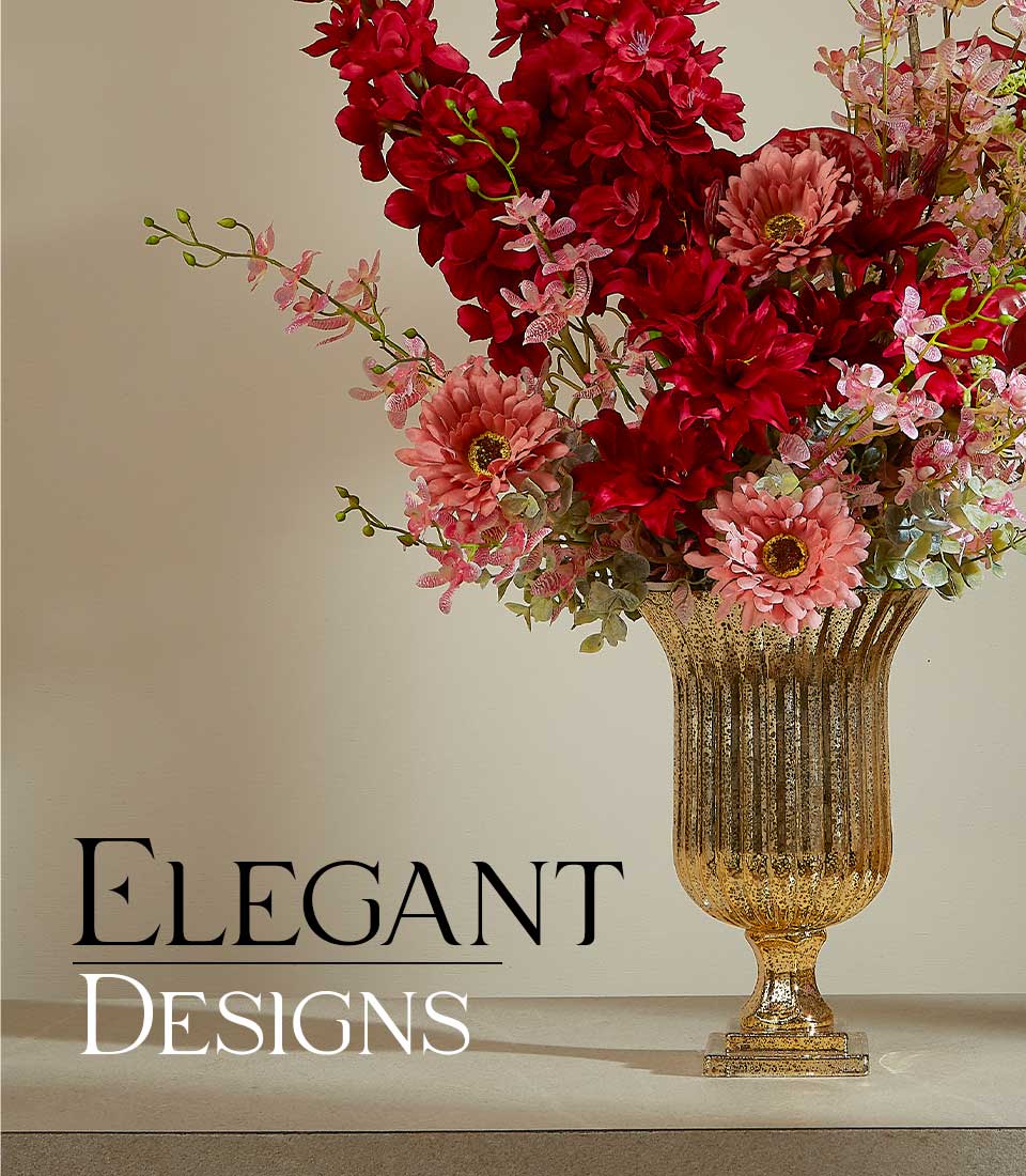 Close-up of elegant red and pink artificial flower arrangement in a tall, fluted gold vase with a 