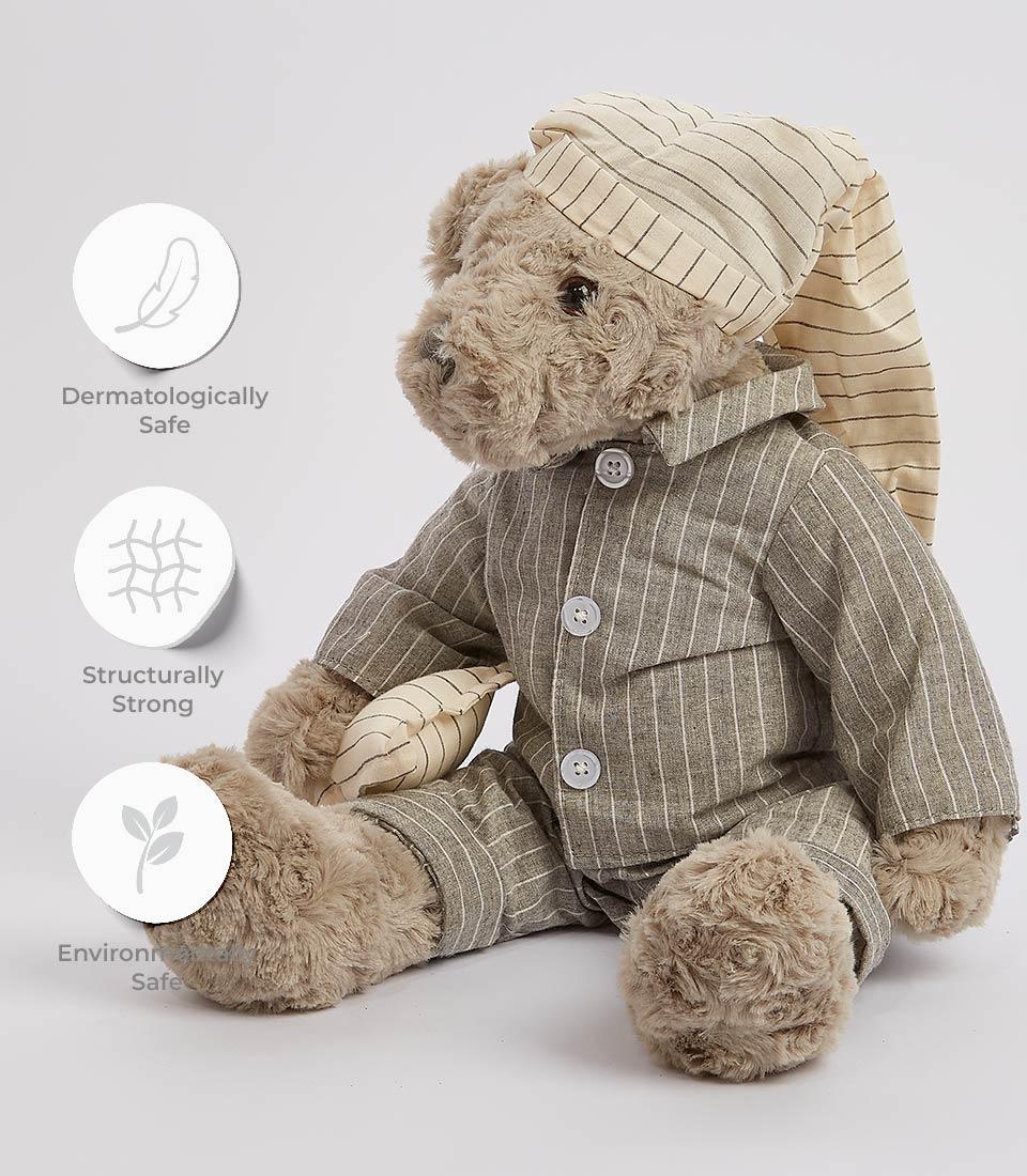 A grey teddy bear in a striped nightgown is pictured holding a blanket. Next to the soft toy are three circular icons with text: 