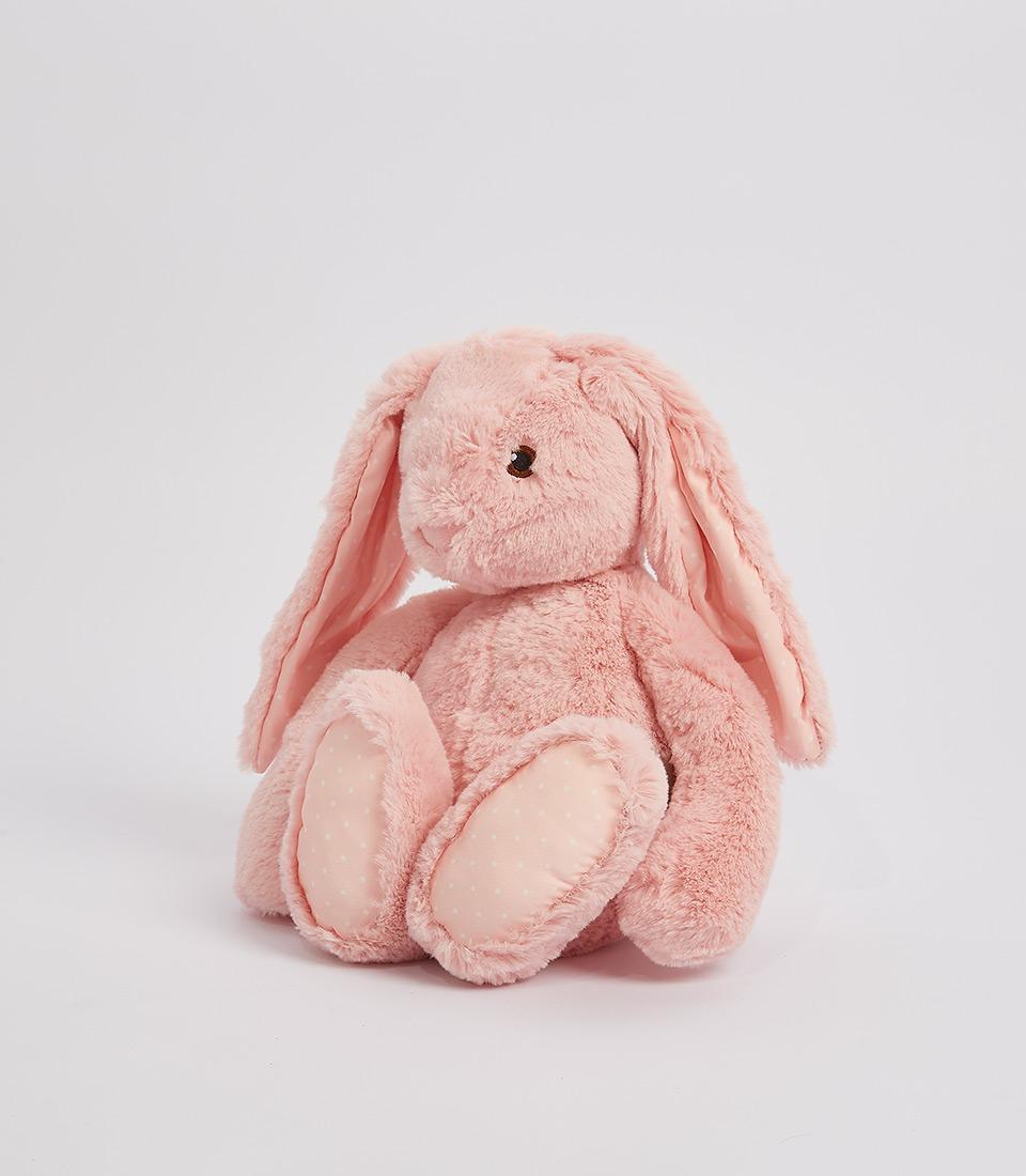 A plush, light pink floppy bunny soft toy with long ears and a fluffy texture. The bunny stands upright with its round body, large feet, and small black eyes giving it a cute and cuddly appearance. The background is plain and light gray.