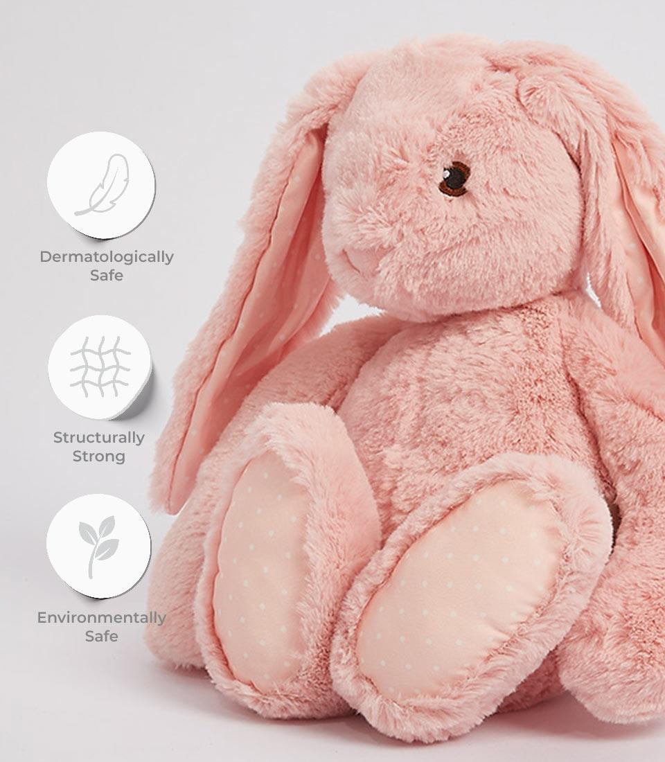 A plush, light pink floppy bunny soft toy with long ears and a fluffy texture. The bunny stands upright with its round body, large feet, and small black eyes giving it a cute and cuddly appearance. The background is plain and light gray. Next to the soft toy are three circular icons with text: 