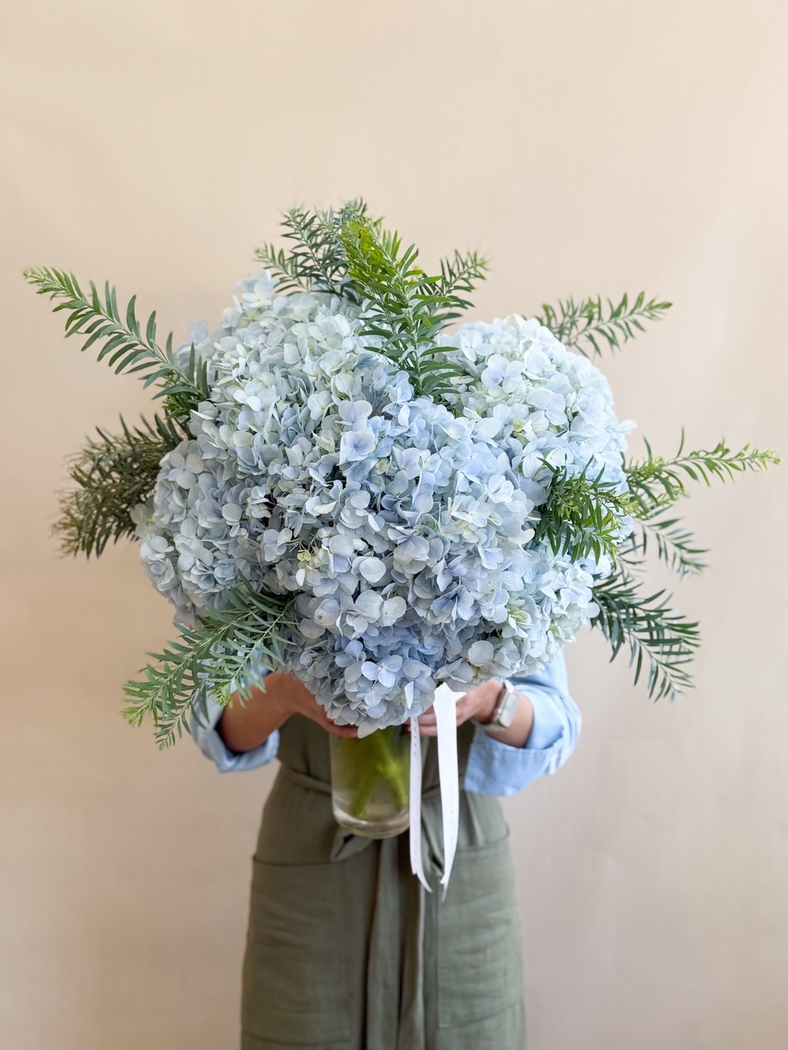Elegant vase of fresh blue hydrangeas with lush greenery.