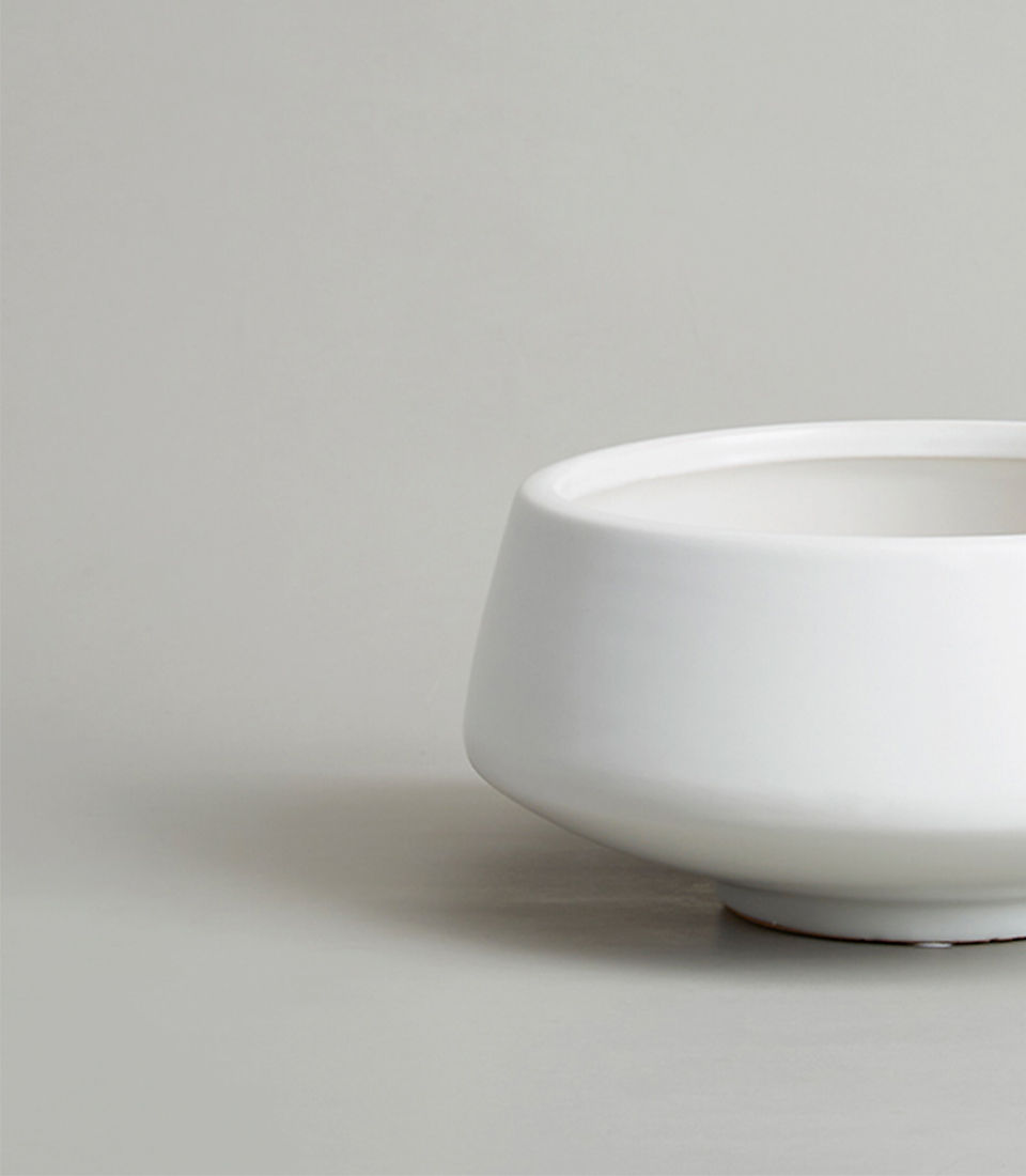 Close-up of a modern white ceramic bowl-shaped vase on a light gray background.