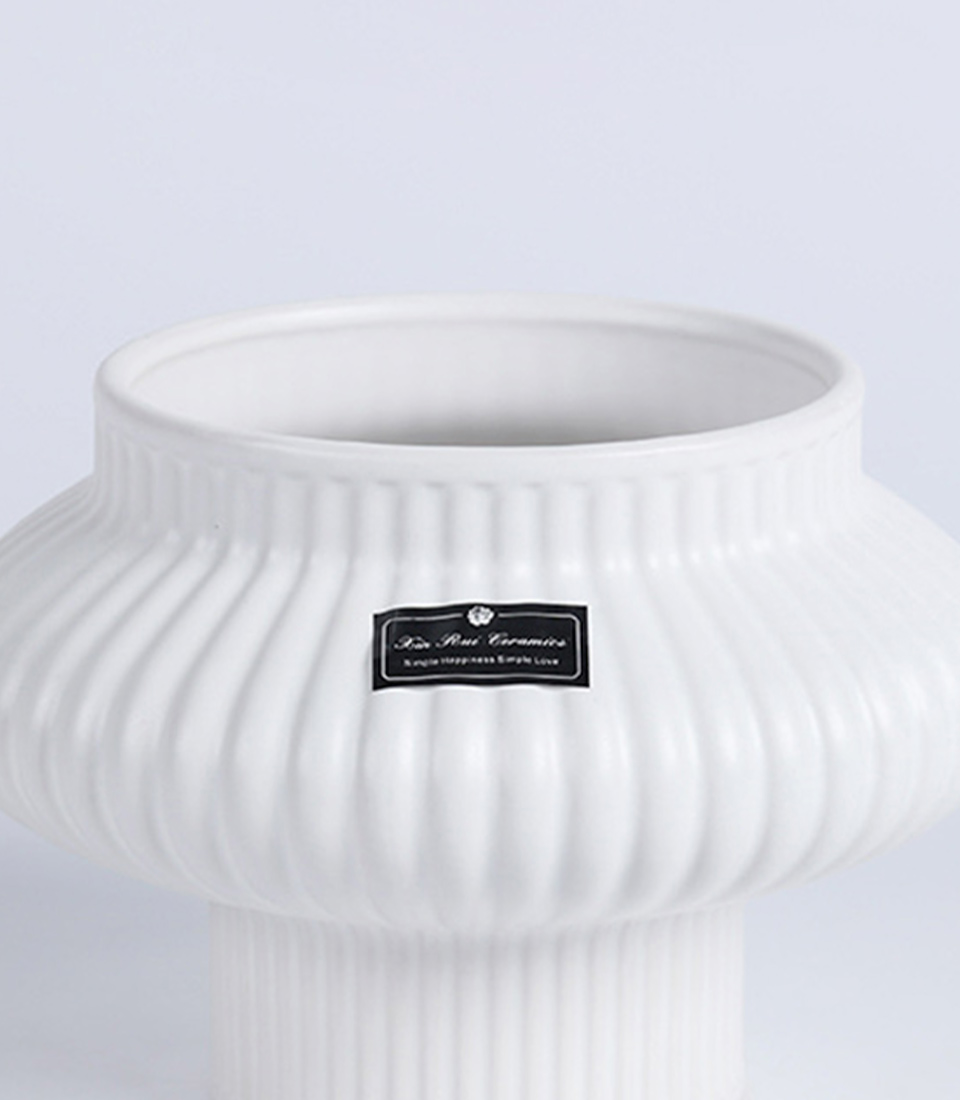 Close-up of a white ribbed ceramic vase with a unique flared design.