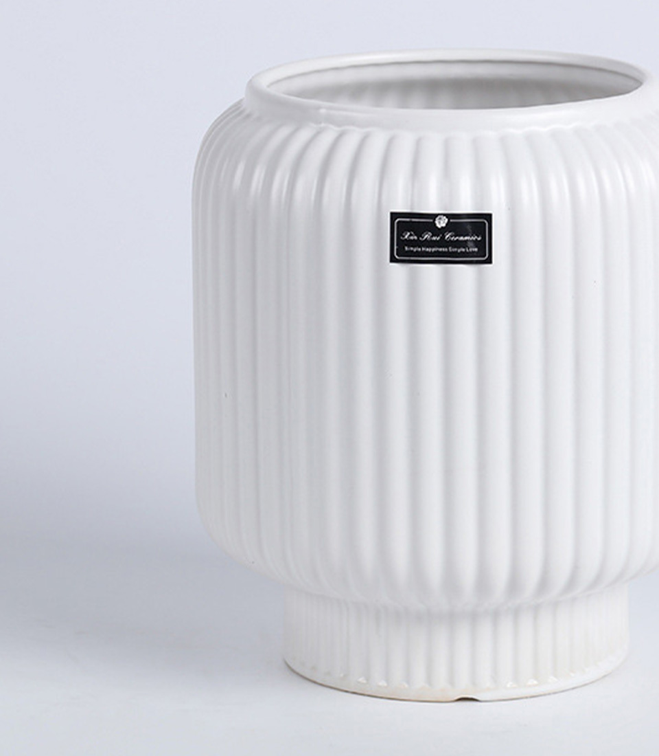 Close-up of a white ribbed ceramic vase with an elevated base.