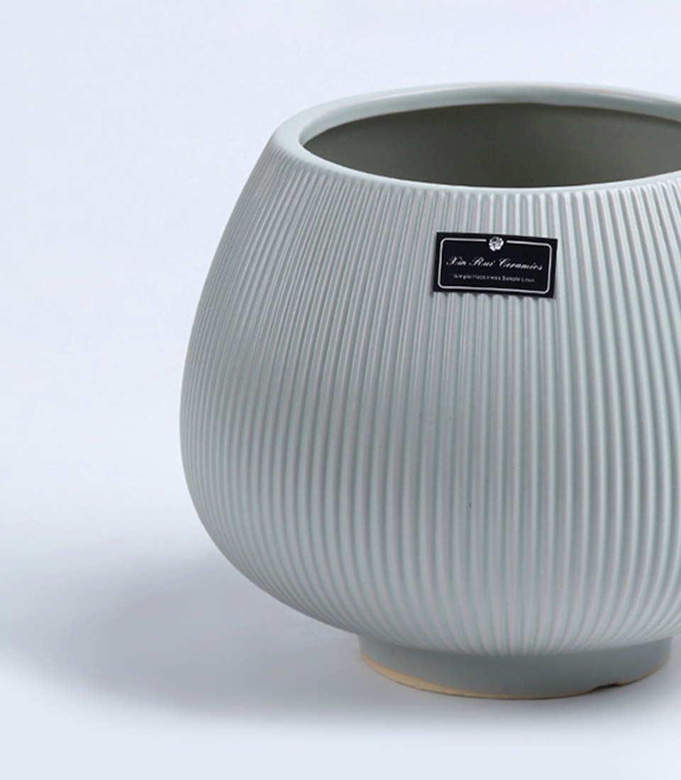 Close-up of a Gray ribbed ceramic vase with a rounded design on a white background.