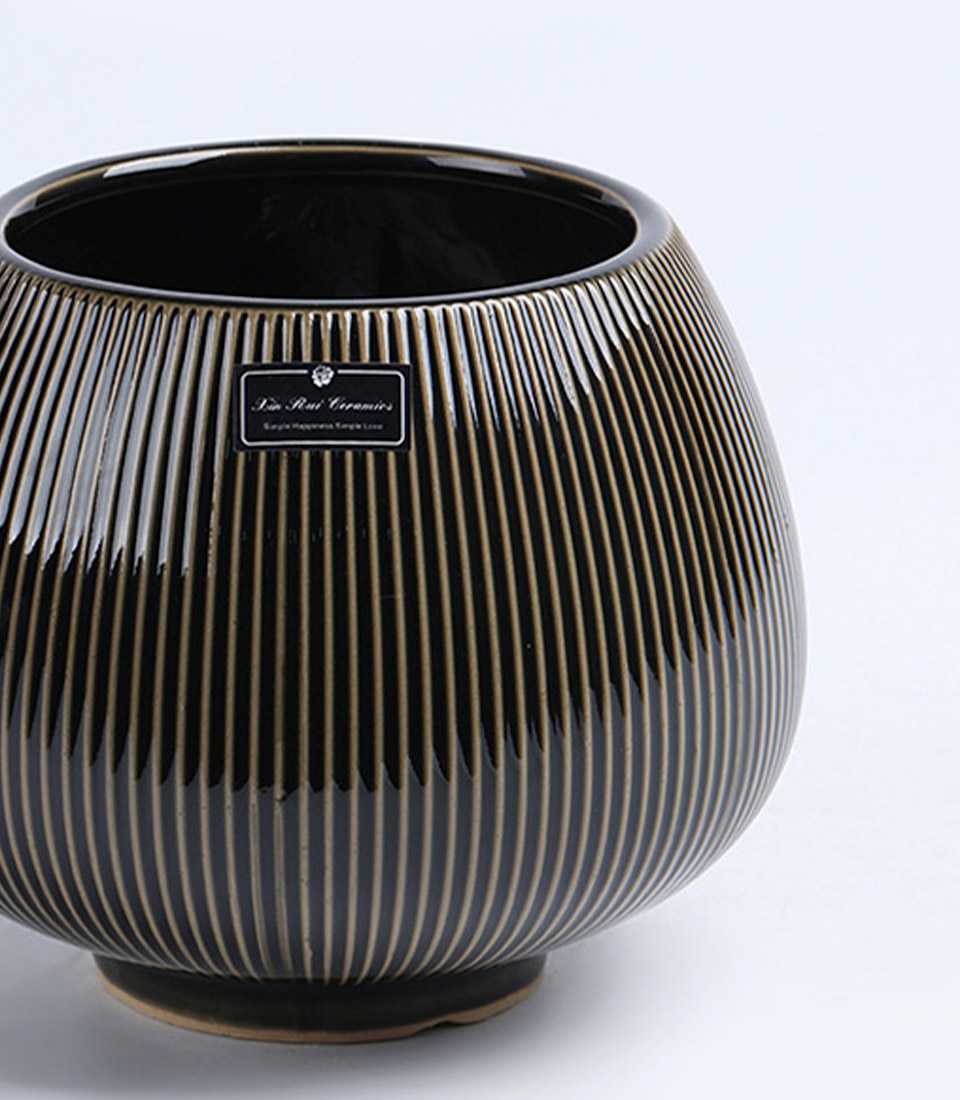 Close-up of a black ribbed ceramic vase with a rounded design on a white background.