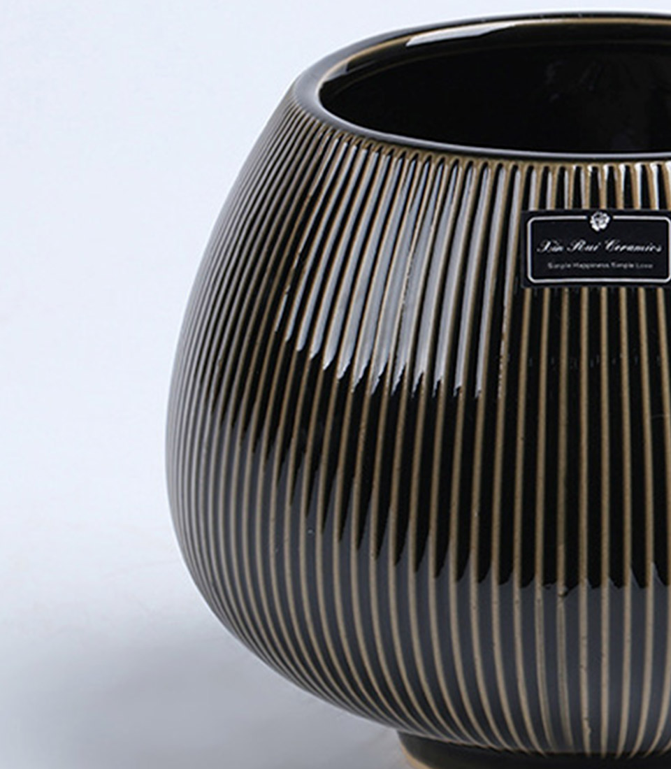 Close-up of a black ribbed ceramic vase with a rounded design on a white background.