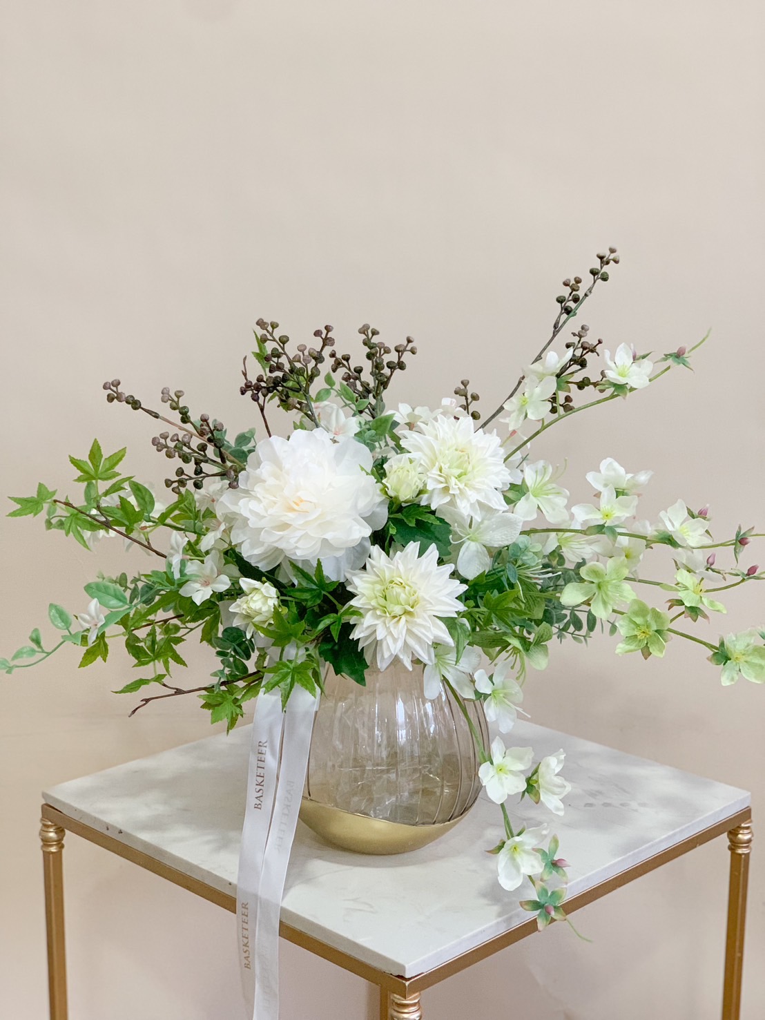 A stunning white artificial floral arrangement in a modern glass vase, featuring lifelike white blooms and lush greenery for a fresh, elegant touch.