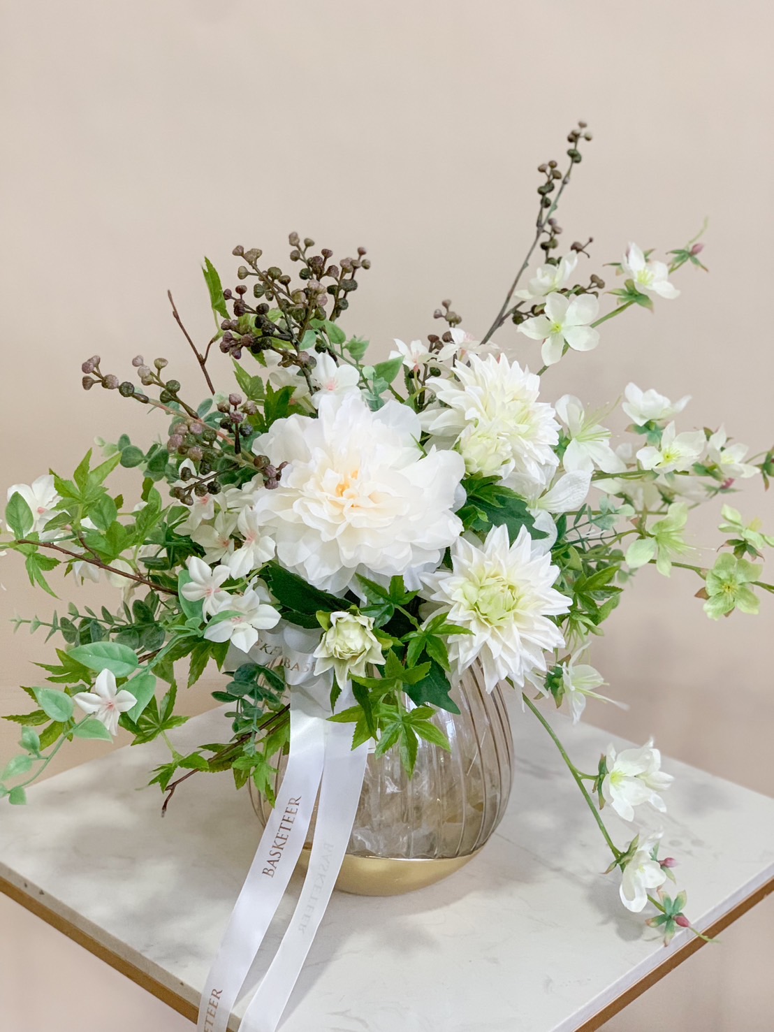 A stunning white artificial floral arrangement in a modern glass vase, featuring lifelike white blooms and lush greenery for a fresh, elegant touch.