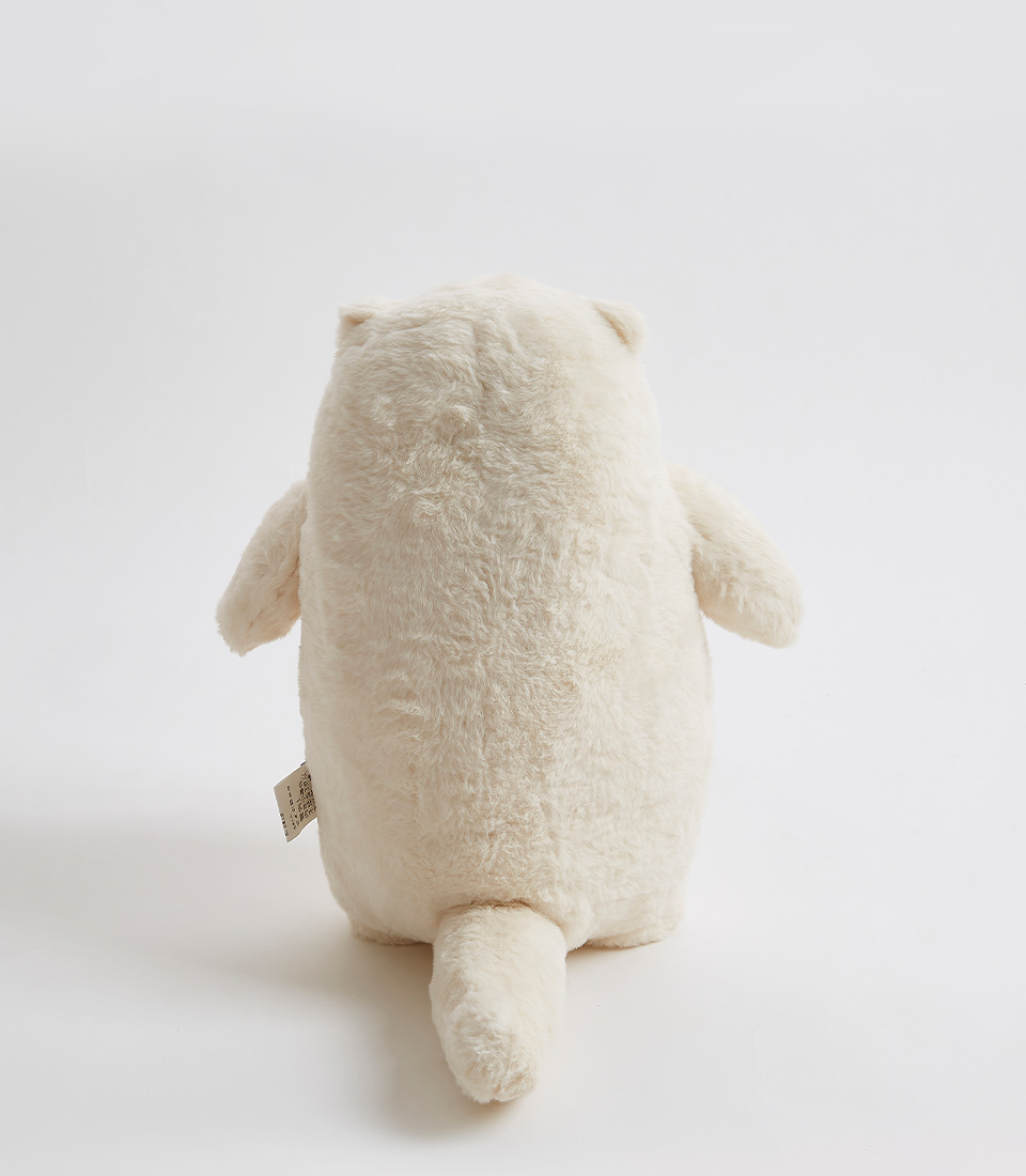cream-colored plush bear viewed from the back, showcasing its fluffy texture and small tail.
