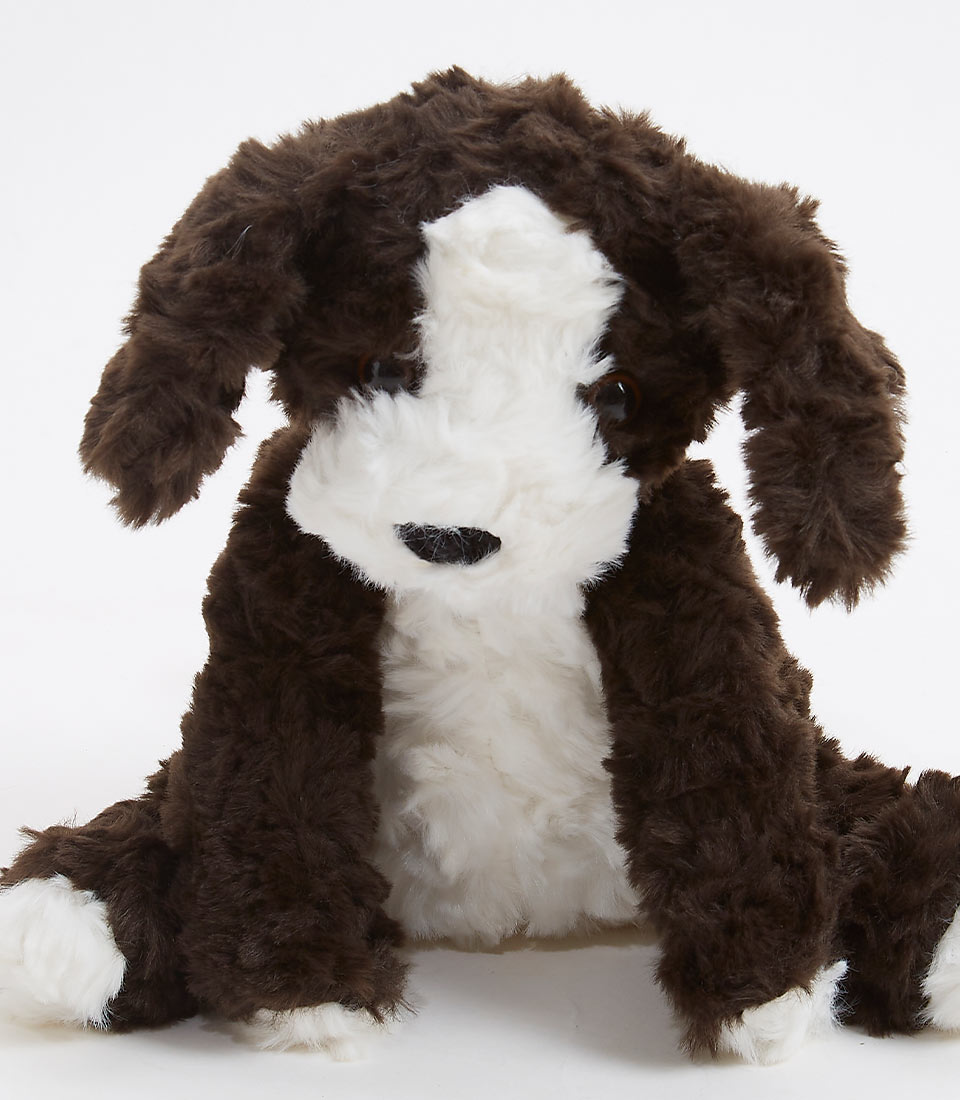 Close-up of a soft and cuddly floppy puppy plush toy, featuring a realistic brown and white fur design, perfect for children and dog lovers