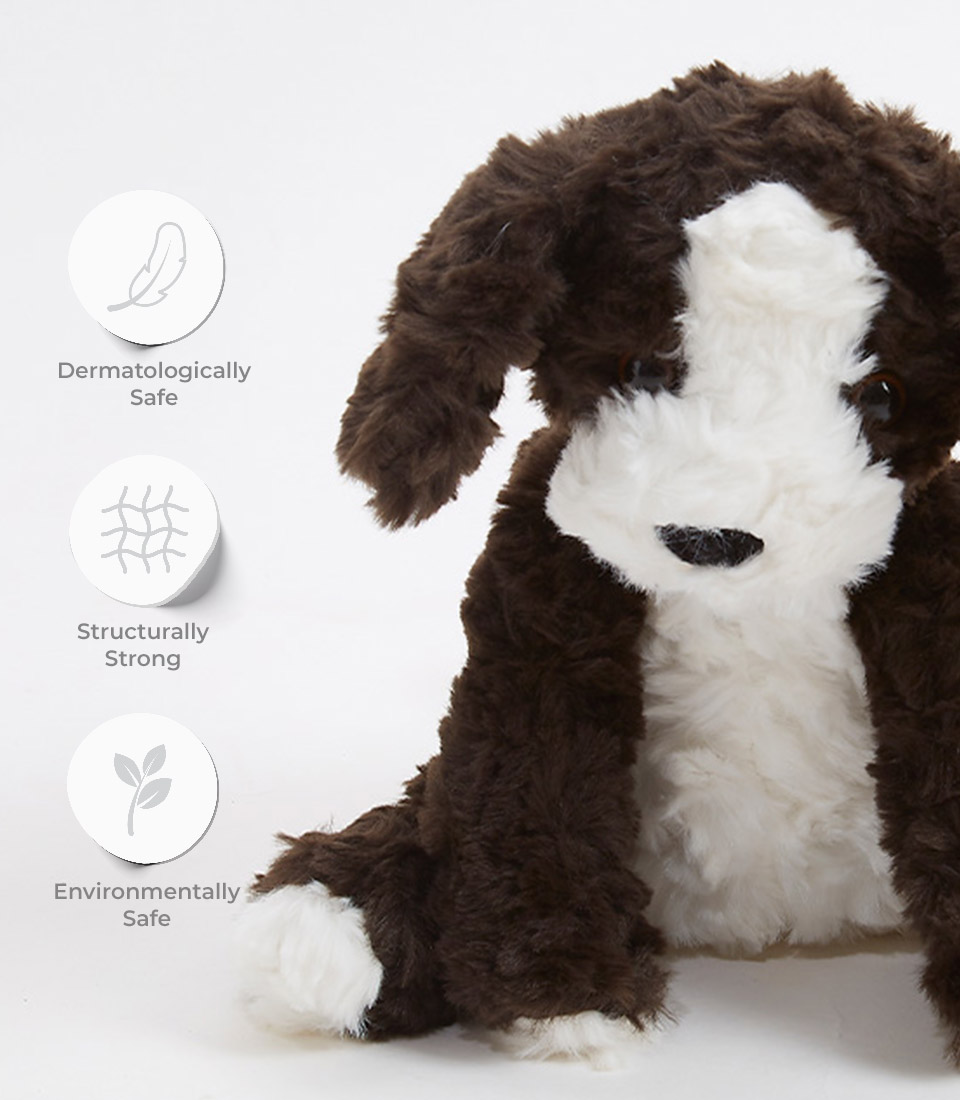 Close-up of a floppy puppy plush toy, showing its soft brown and white fur, with dermatologically safe, structurally strong, and environmentally safe icons displayed on the left.