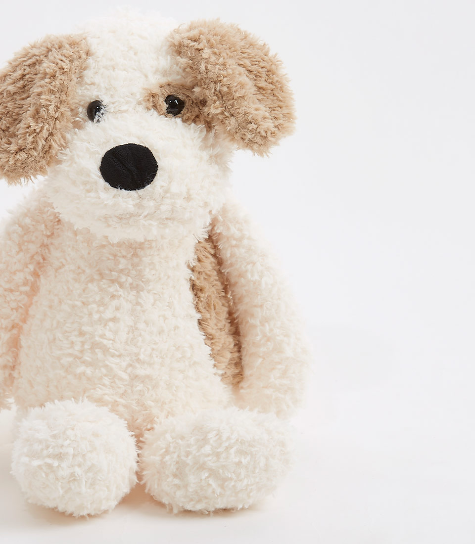 Close-up of a beige and brown plush puppy toy, showcasing its soft, fluffy texture and adorable face with black nose and eyes