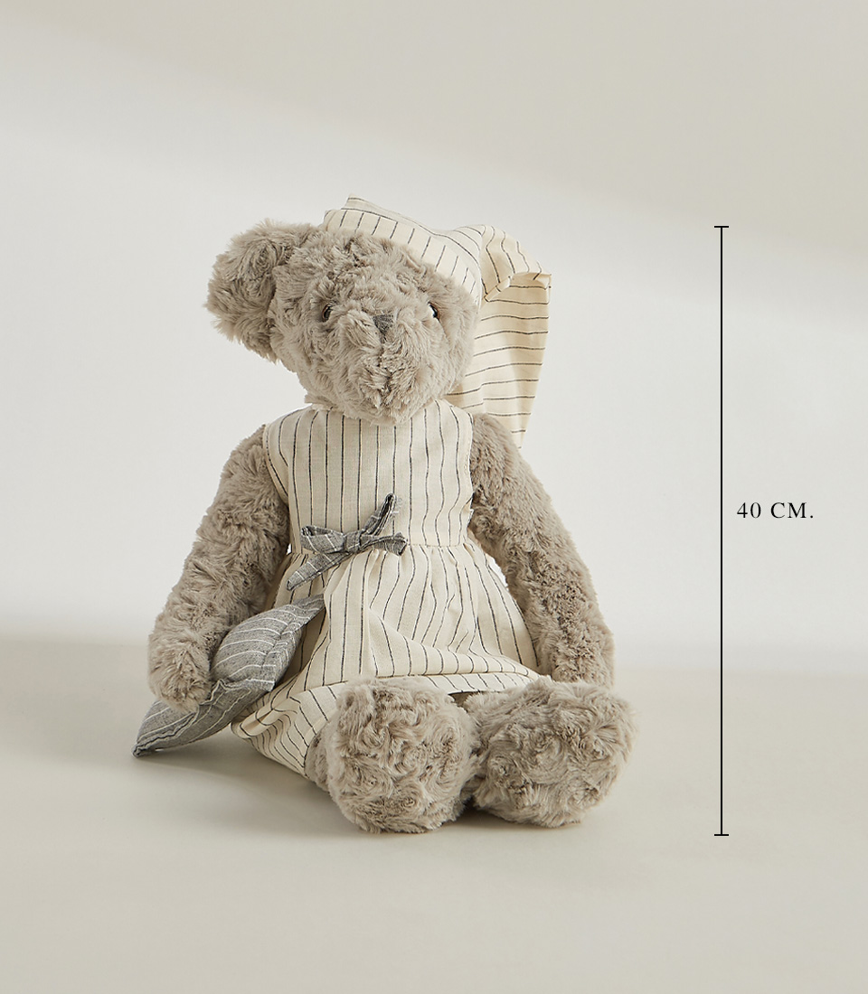 A grey teddy bear wearing a striped nightgown and matching nightcap, standing and ready for bedtime, set against a light gray background.