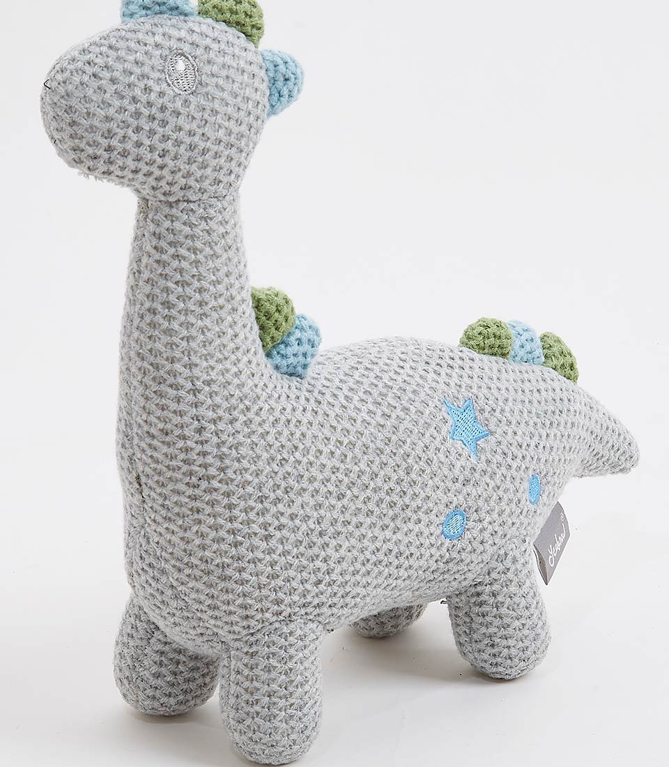 Close-up view of a handcrafted crocheted dinosaur plush toy, with a soft grey exterior and pastel blue and green accents. The toy features a friendly design with embroidered eyes and small details, making it perfect for newborns and young children.