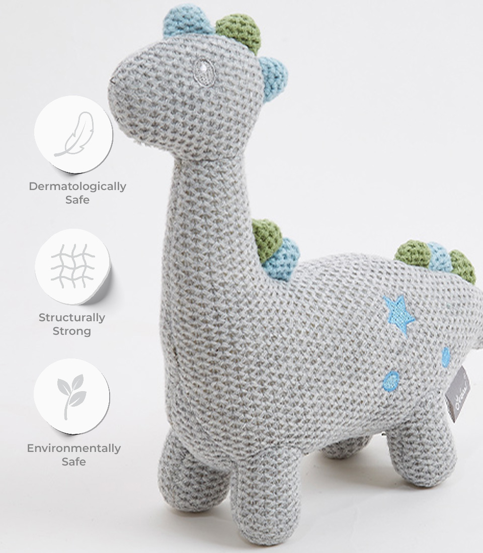 Close-up view of a handcrafted crocheted dinosaur plush toy, with a soft grey exterior and pastel blue and green accents. The toy features a friendly design with embroidered eyes and is dermatologically safe, structurally strong, and environmentally safe, making it perfect for newborns and young children.