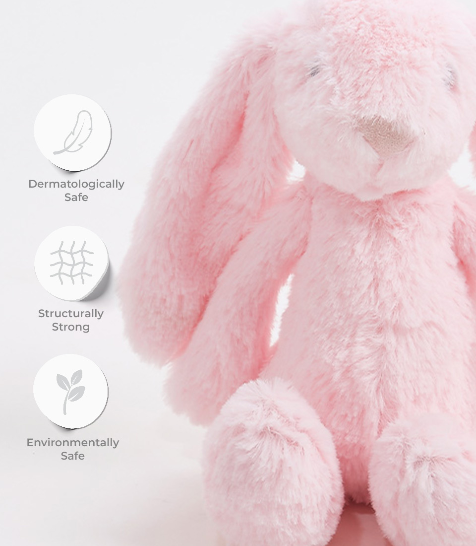 Close-up of a soft pink plush bunny toy with long floppy ears and an embroidered face, labeled as dermatologically safe, structurally strong, and environmentally safe.
