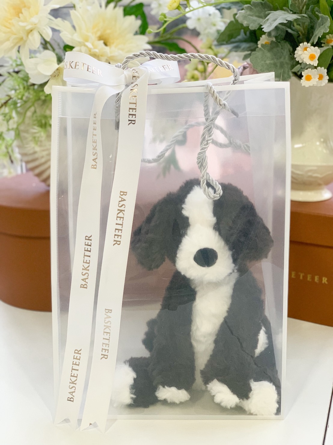 Adorable black and white plush puppy in a semi-transparent Basketeer gift bag with white ribbon.