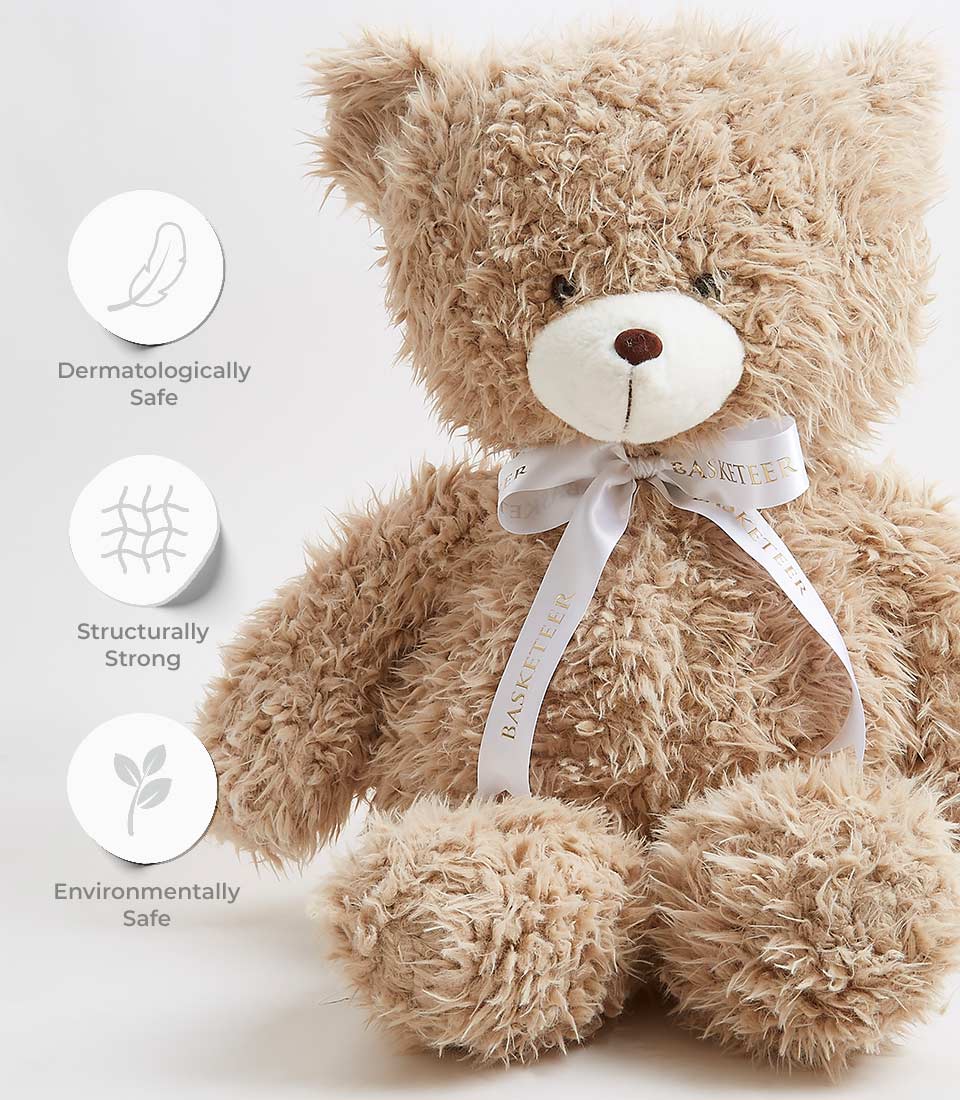 A fluffy brown teddy bear with a white bow around its neck sits upright. The bow is labeled with 