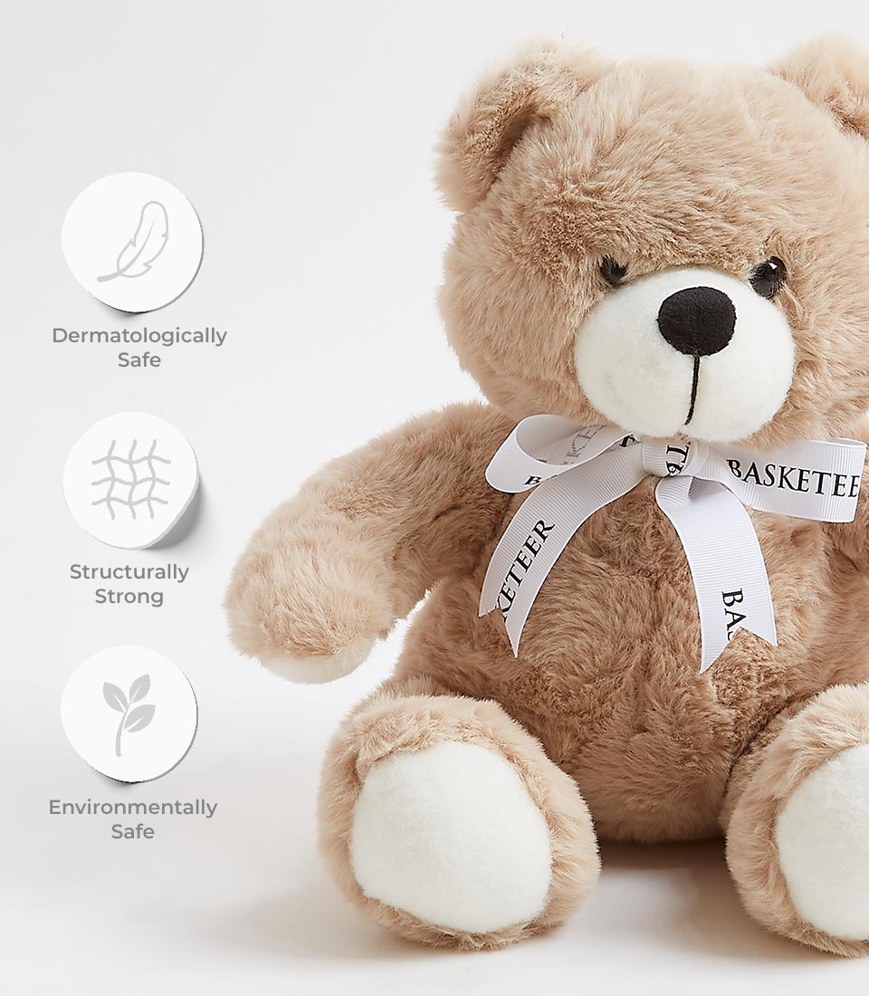 An adorable tan teddy bear soft toy with a white ribbon reading 