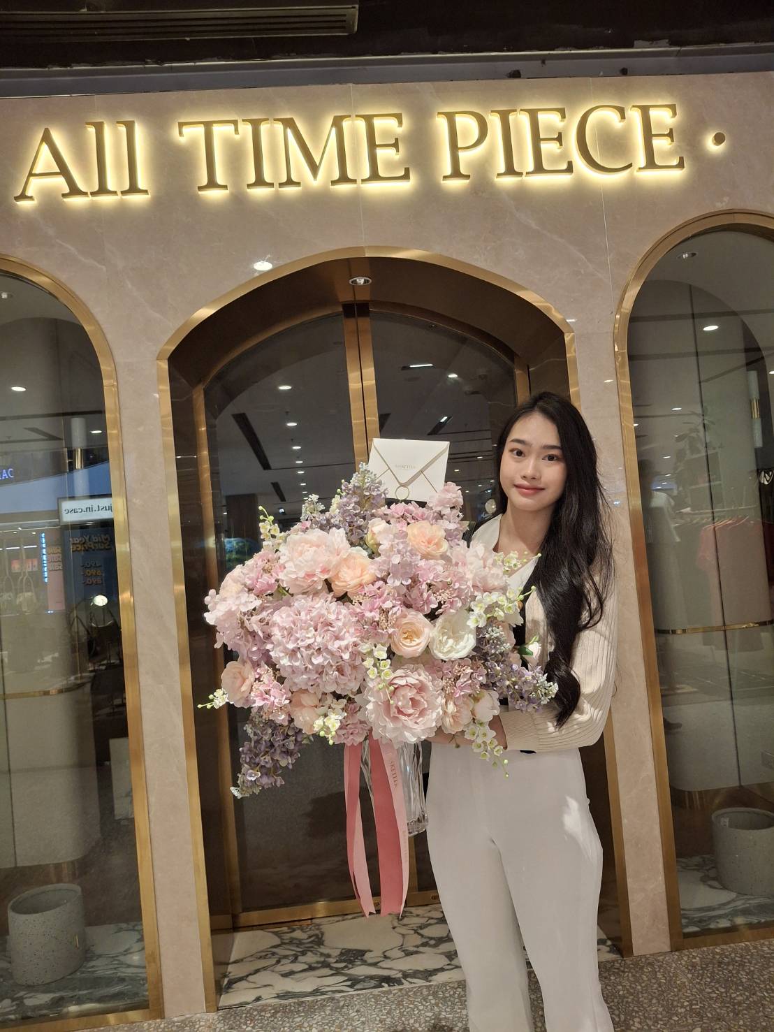 A woman in a white outfit stands gracefully in front of a store with the sign 