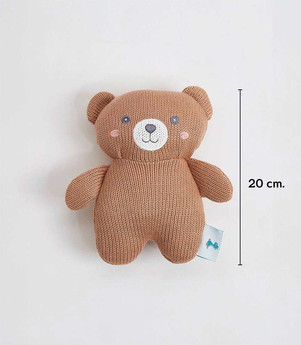 A knitted brown teddy bear with a textured surface, featuring stitched eyes, nose, and mouth, and light pink cheeks. The bear is 20 cm tall, as indicated by a measurement line next to it. A small blue tag is attached to the bear's side.