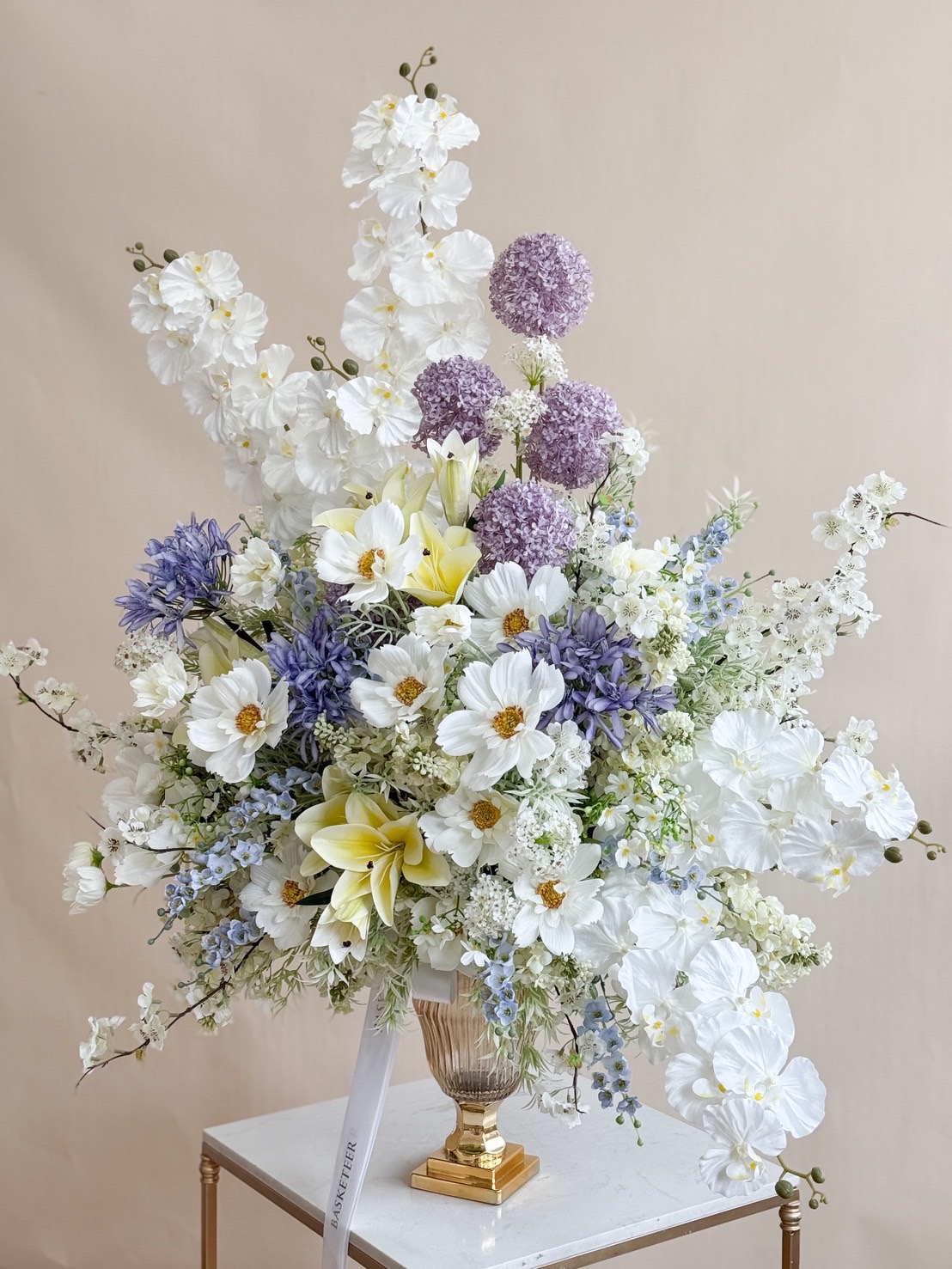 Elegant tall vase with luxury white, purple, and yellow flowers including orchids, lilies, and cosmos for grand events and celebrations.