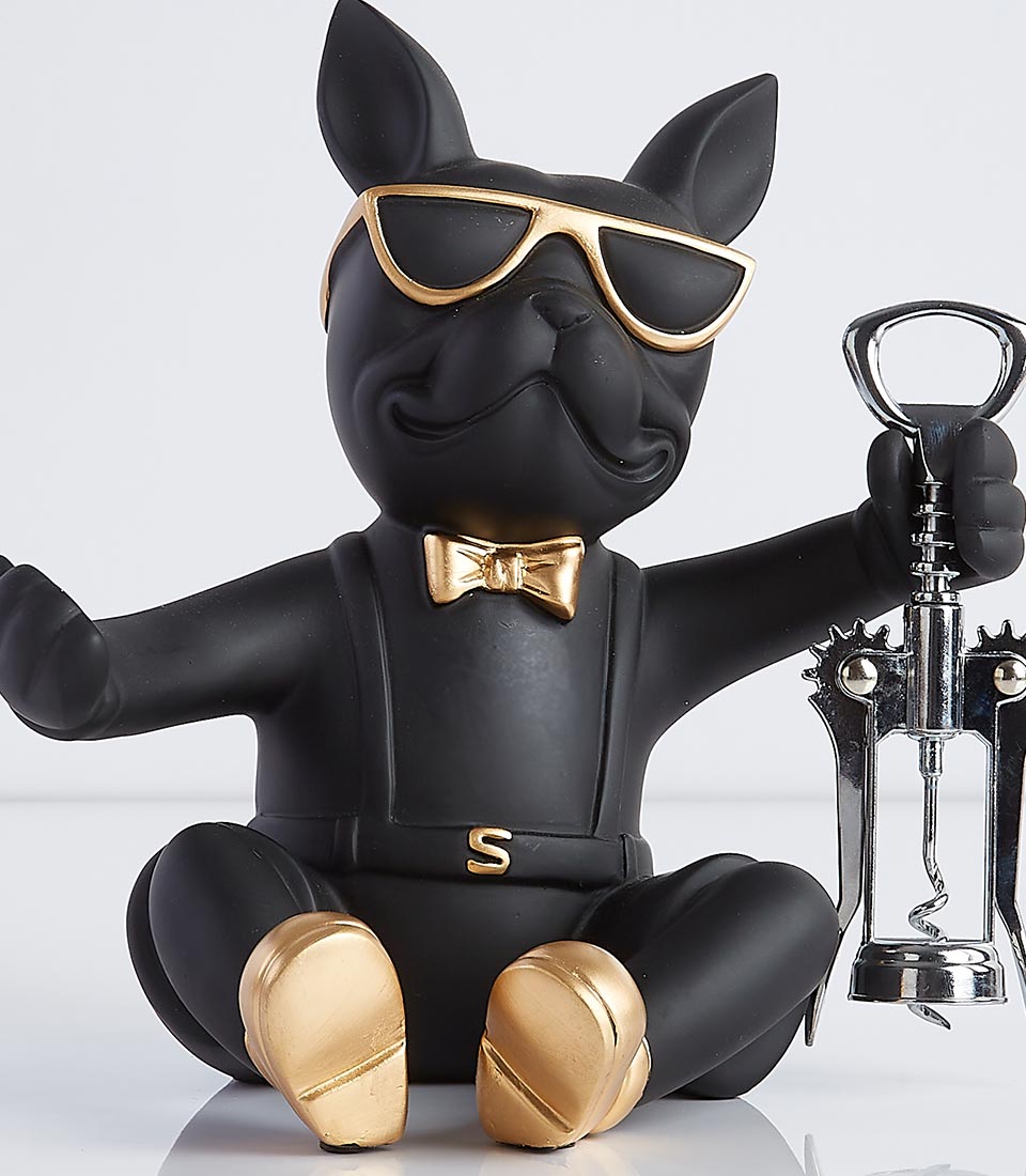 Black bulldog figurine wearing sunglasses and a bowtie, holding a corkscrew and designed to hold a wine bottle.