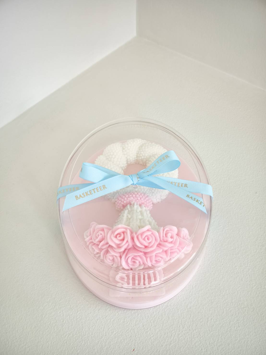 Pink coconut jelly with white jasmine garland and pink roses, tied with blue “Basketeer” ribbon, “รักแม่” message, Mother’s Day gift.
