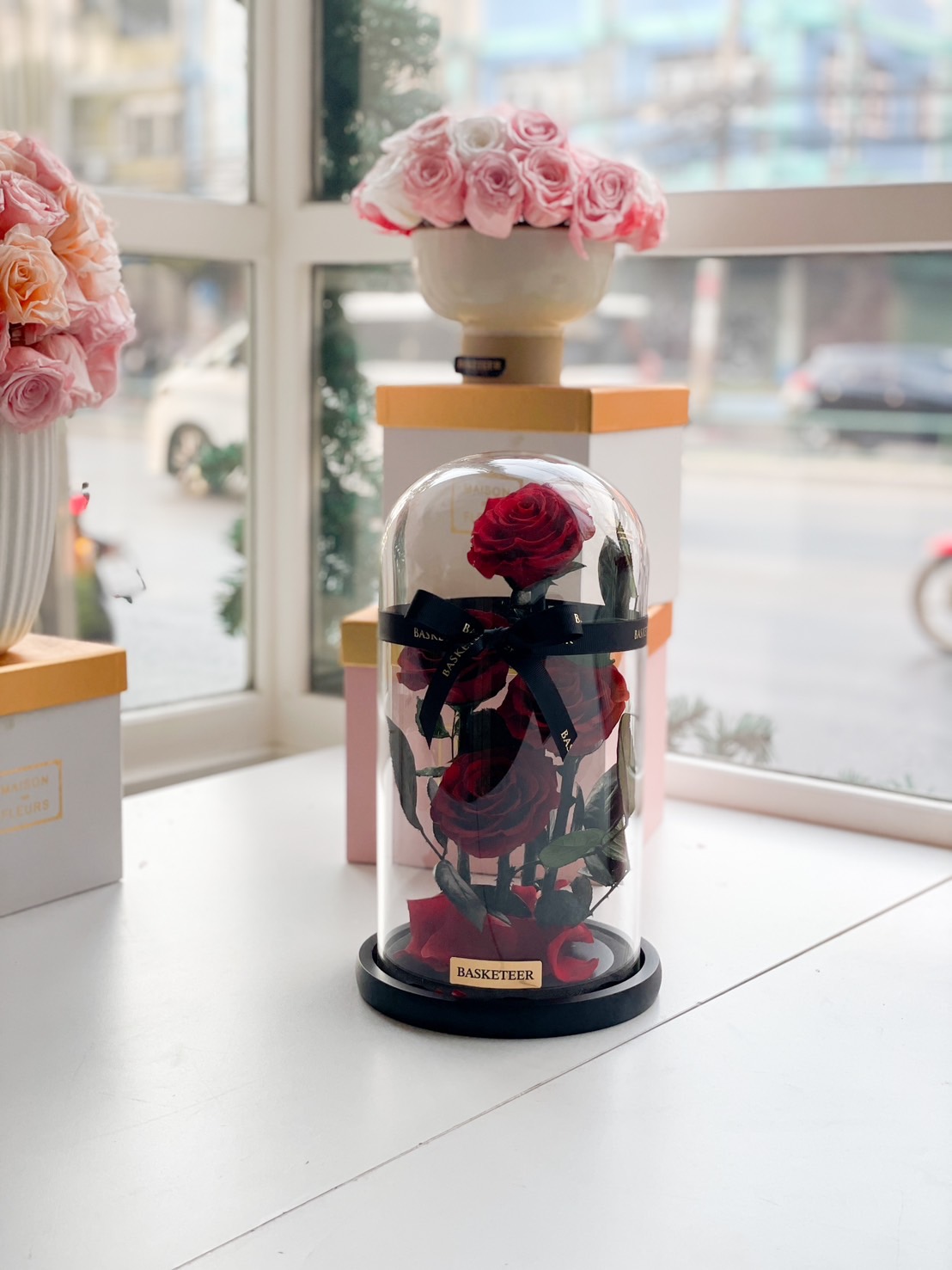 A preserved red rose in a glass dome with an elegant black base, symbolizing eternal love and beauty, wrapped with a luxury Basketeer ribbon.